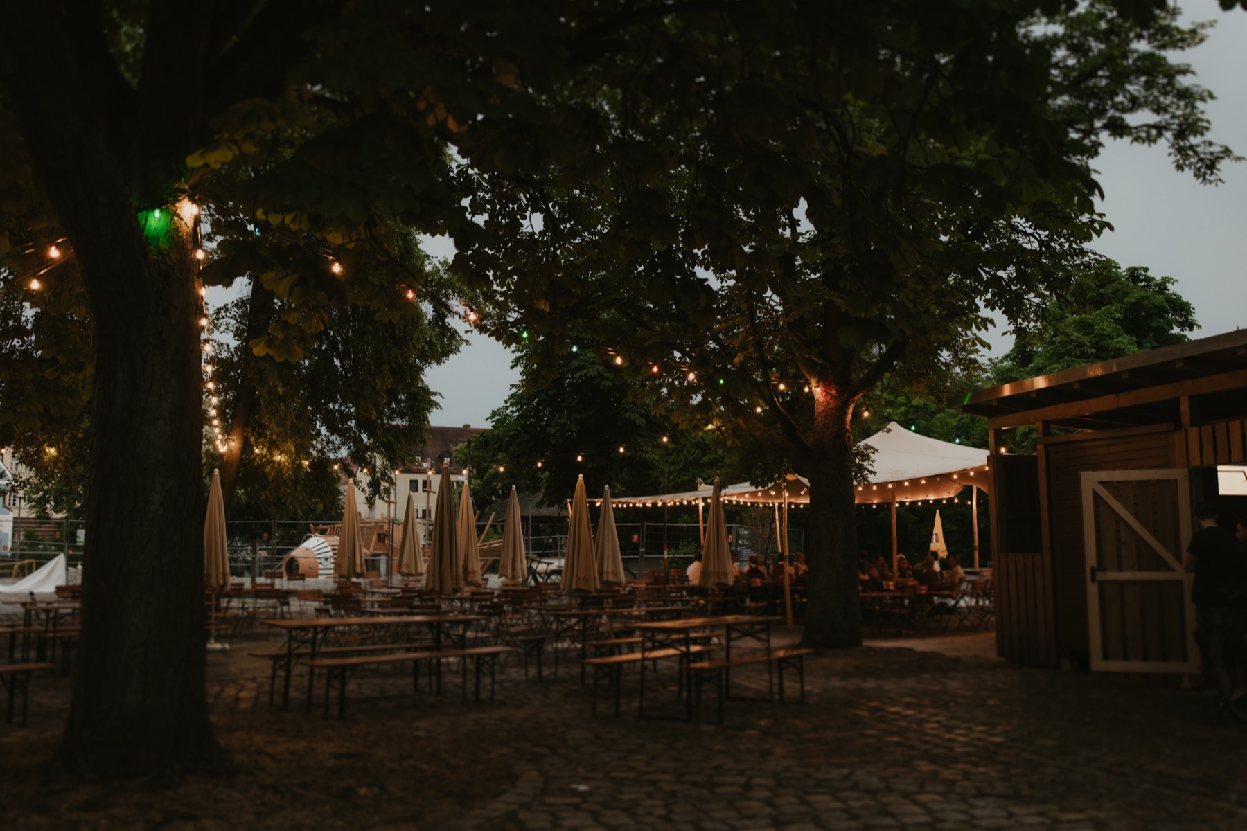 Biergarten im Stadtpark am Abend unter Lichterketten